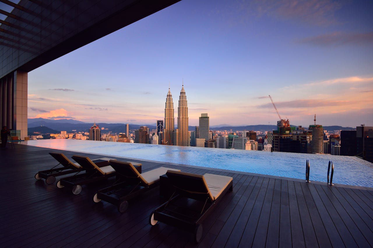 Relax by a luxury infinity pool with stunning Kuala Lumpur skyline and Petronas Towers at twilight.