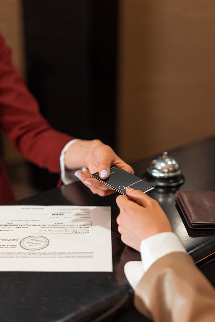 Offerings A hotel receptionist hands a key card to a guest over the counter, with documents visible.